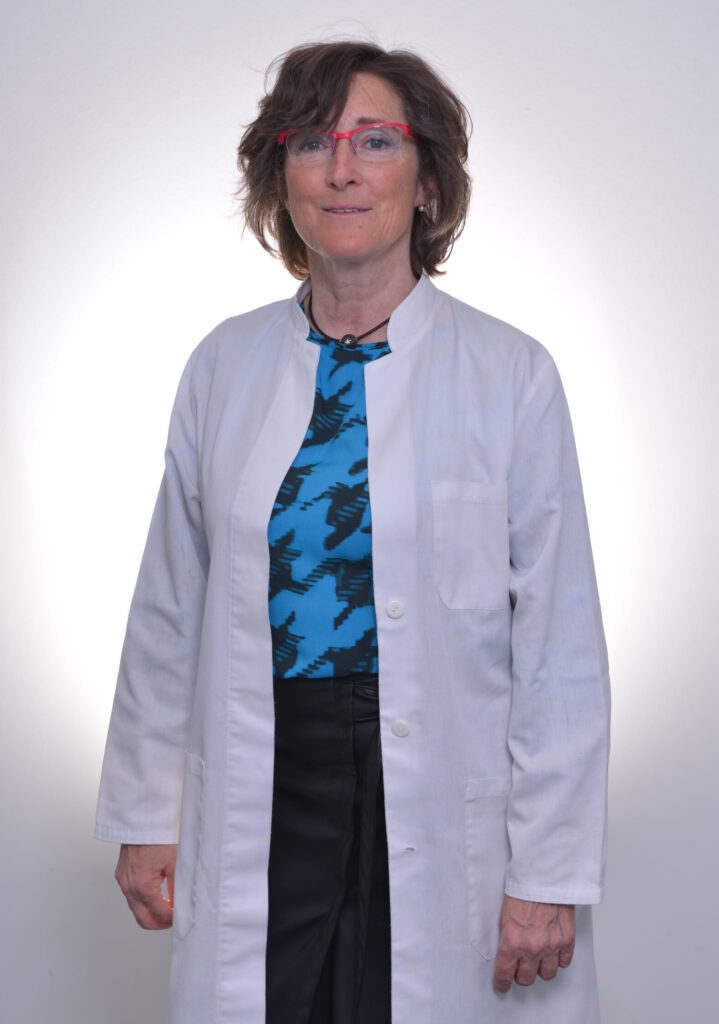 Ärztin im Kittel mit Brille vor hellem Hintergrund.